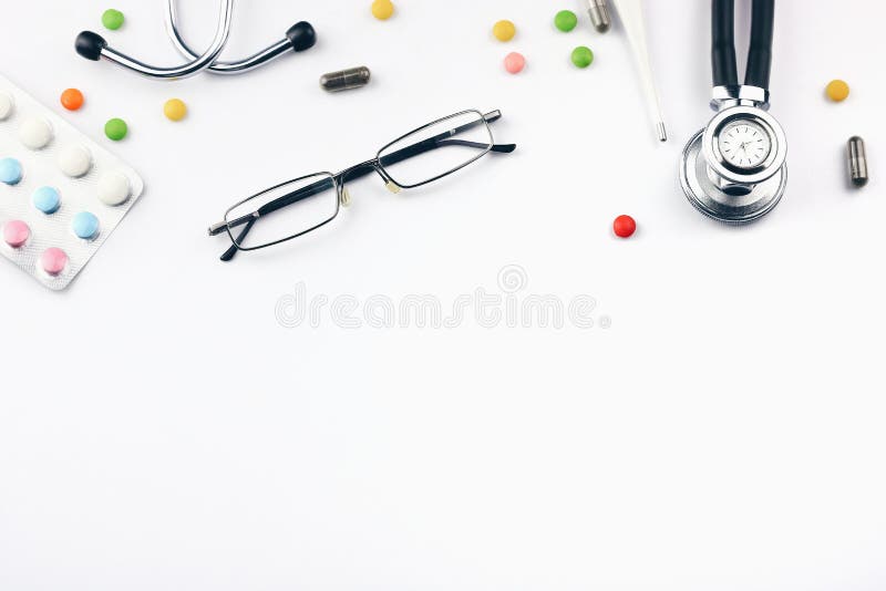 Modern doctor desk table with stethoscope, glasses and pills. Top view with copy space, flat lay