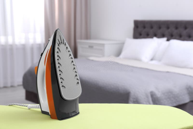 Modern Electric Iron on Board in Bedroom. Laundry Day Stock Image