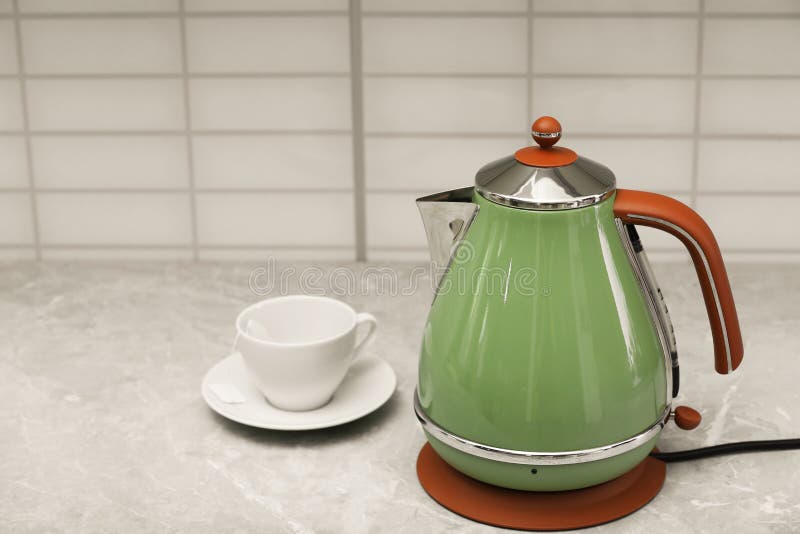 Modern Electric Kettle and Cup on Grey Kitchen Counter. Space for Text