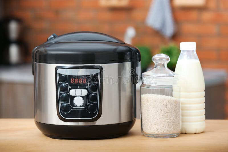 Modern Electric Multi Cooker, Rice and Milk on Table Stock Photo