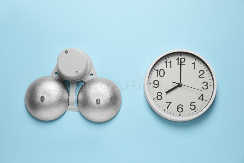Modern electrical school bell and clock on light blue wall stock image
