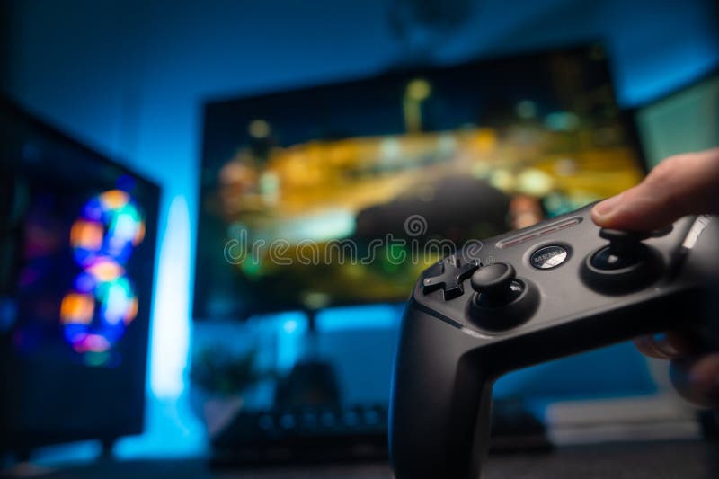 Close up of gamer holding controller and playing video games on computer.  Woman using joystick to play online digital games in front of monitor.  Person with modern gaming equipment Stock Photo 