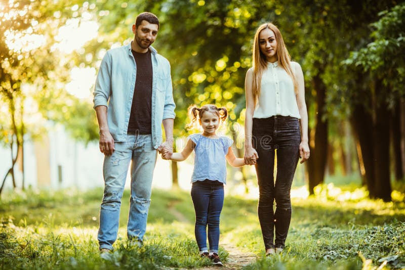 Modern, fadern och lilla flickan som går i sommar, parkerar och har gyckel royaltyfria bilder Modern, fadern och lilla flickan som går i sommar, parkerar och har gyckel royaltyfria bilder
