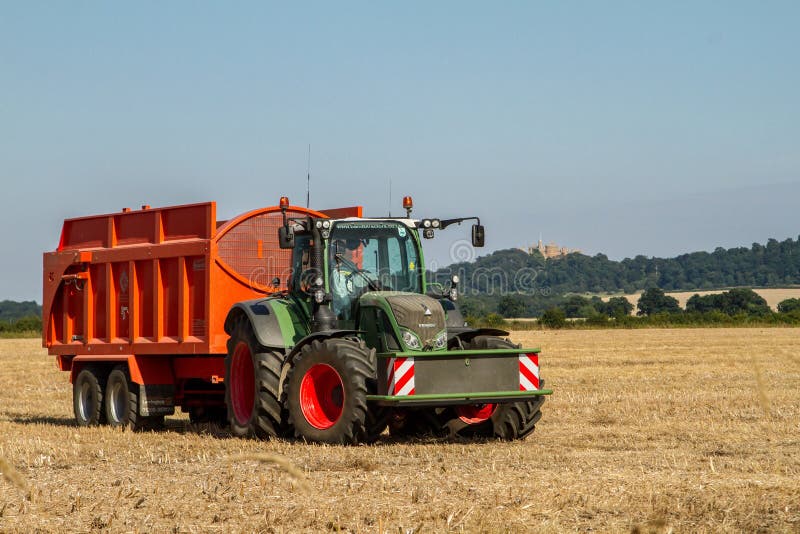 Modern Fendt tractor pulling orange trailer royalty free stock image