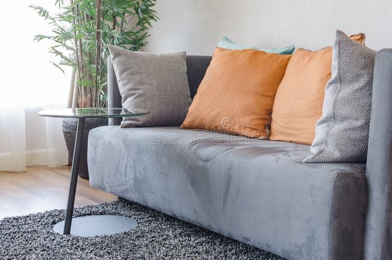 Modern Grey Sofa with Orange Pillows and Round Black Table Stock Image