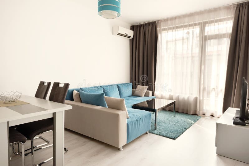 Modern helder en comfortabel woonkamer binnenlands ontwerp met bank, eettafel en keuken Grijze en turkooise blauwe zitslaapkamer stock afbeeldingen Modern helder en comfortabel woonkamer binnenlands ontwerp met bank, eettafel en keuken Grijze en turkooise blauwe zitslaapkamer stock afbeeldingen