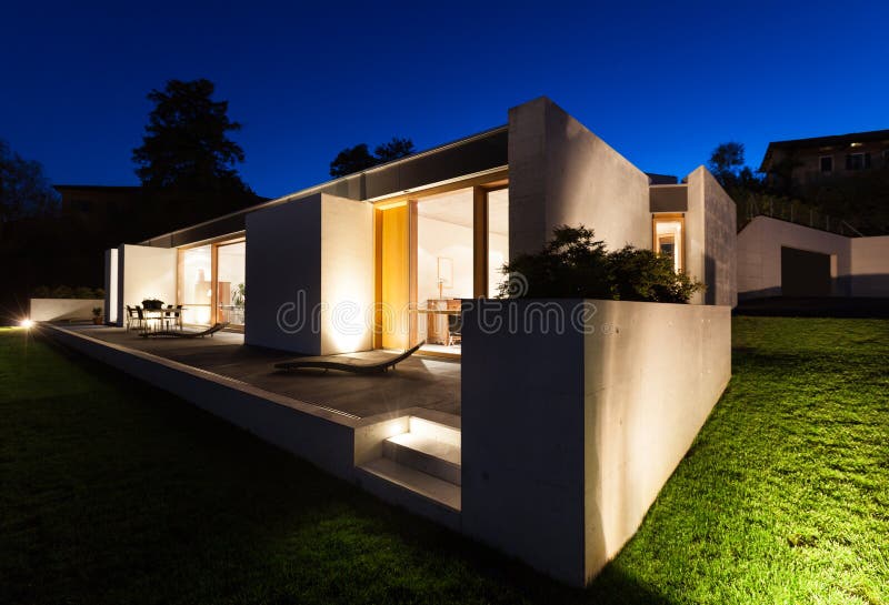 Beautiful modern house in cement, view from the garden, night scene