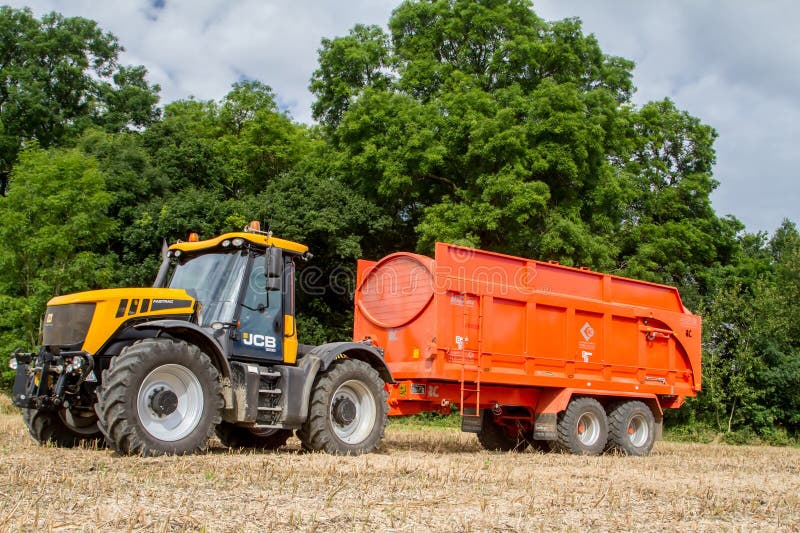 Modern jcb tractor pulling orange trailer stock image