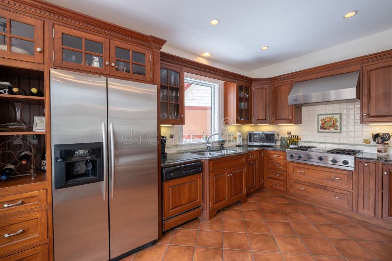 Modern kitchen interior with an oven, fridge, sink, faucet, and a wooden cabinet