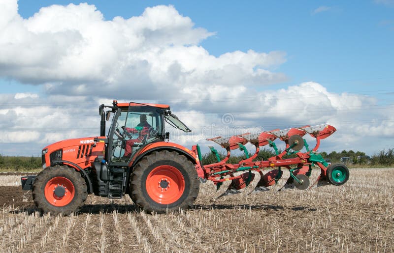 Modern Kubota tractor pulling a plough