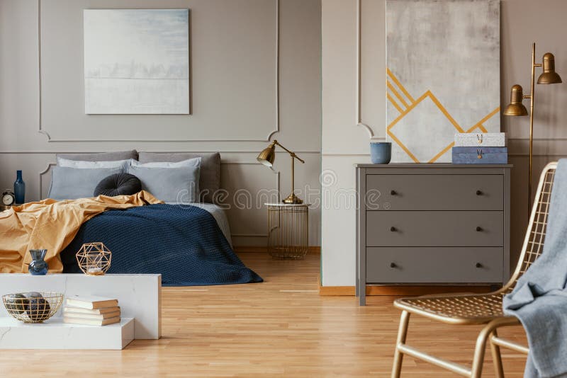 Lamp on nightstand table next to king size bed in grey bedroom interior