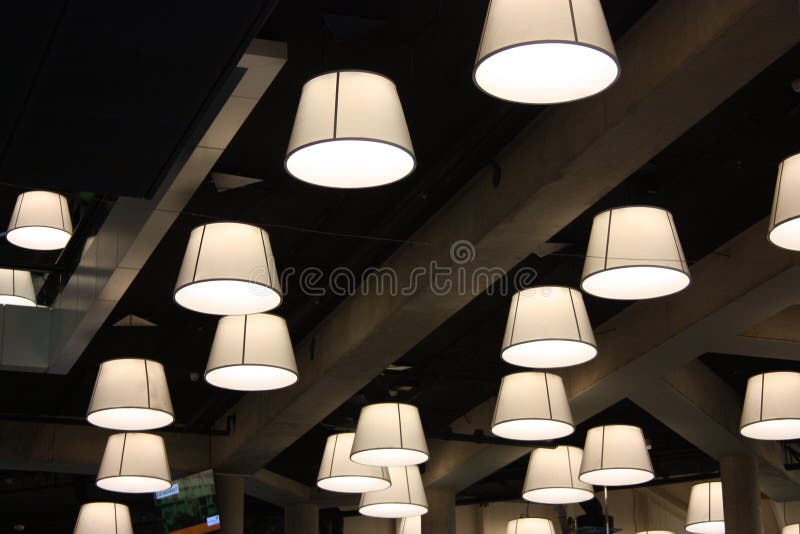 Modern lamps and bulbs hanging from the ceiling radiate light in an office. ceiling of the central library of rotterdam.