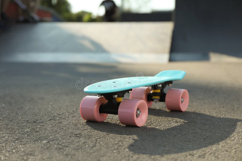 Modern Light Blue Skateboard with Pink Wheels on Asphalt Road Outdoors