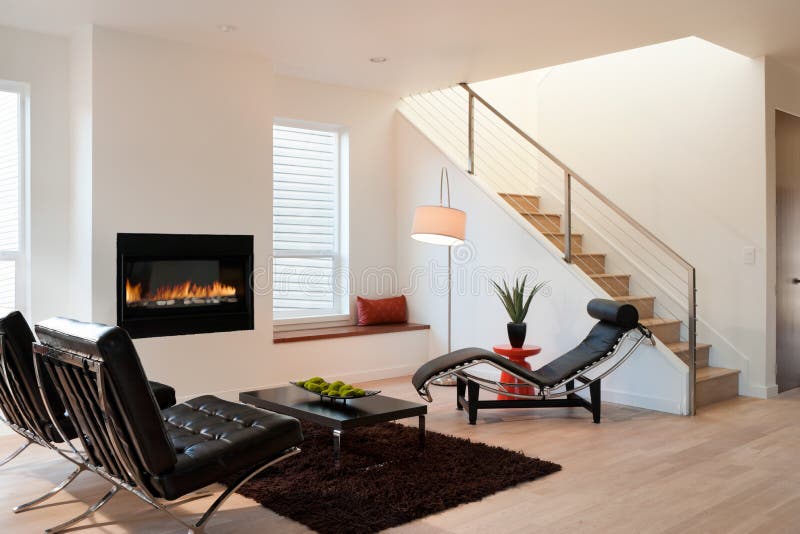 Horizontal shot of a modern living room in an upscale home with lounge chairs, and view of stairs and fireplace. Horizontal shot of a modern living room in an upscale home with lounge chairs, and view of stairs and fireplace.