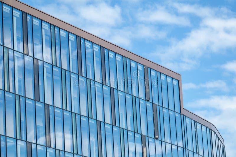 Modern minimalist glass building with clouds and sky reflecting royalty free stock images