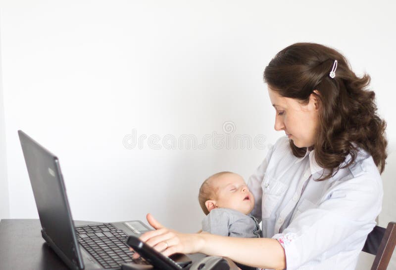 Modern mother holding baby while working in office
