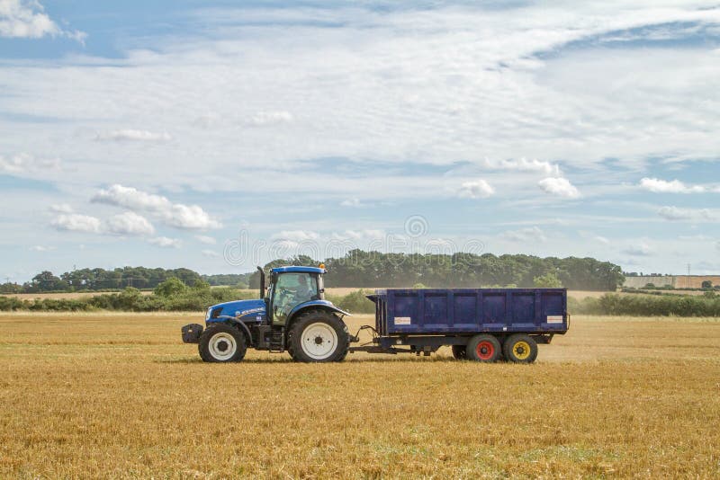 Modern New Holland tractor pulling blue trailer royalty free stock images