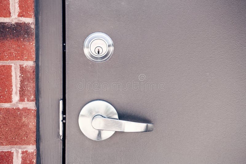 Modern new metallic grey shiny keyhole on door background. Front view of key lock and door handle