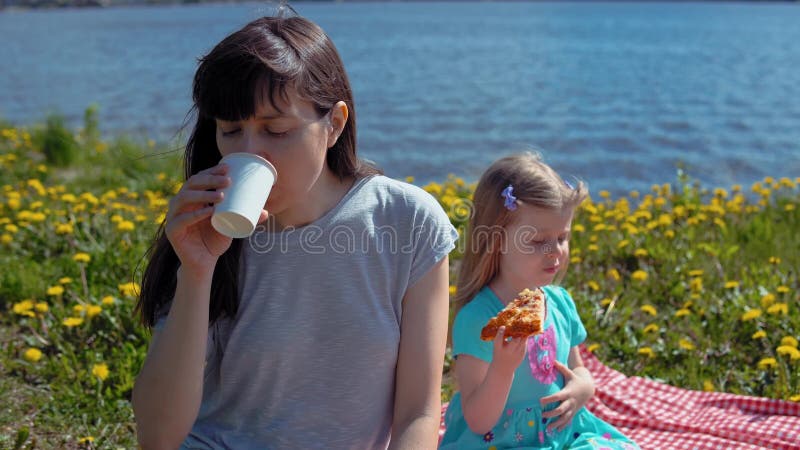 Modern och dottern äter pizza vid kusthavet