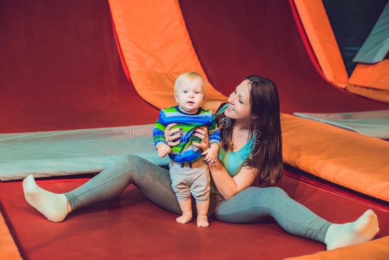 Modern och hennes sonbanhoppning på en trampolin i kondition parkerar och D royaltyfri fotografi Modern och hennes sonbanhoppning på en trampolin i kondition parkerar och D royaltyfri fotografi