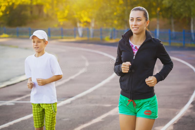 Modern och sonen är köra eller jogga för sport utomhus arkivfoto Modern och sonen är köra eller jogga för sport utomhus arkivfoto