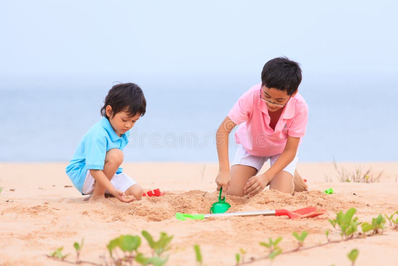 Modern och söner spelar på den tropiska stranden