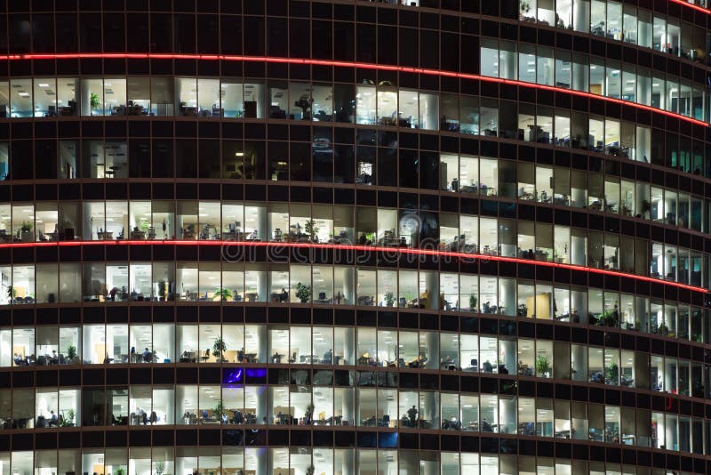 Modern office building with big windows at night, in windows light shines. Modern office building with big windows at night, in windows light shines