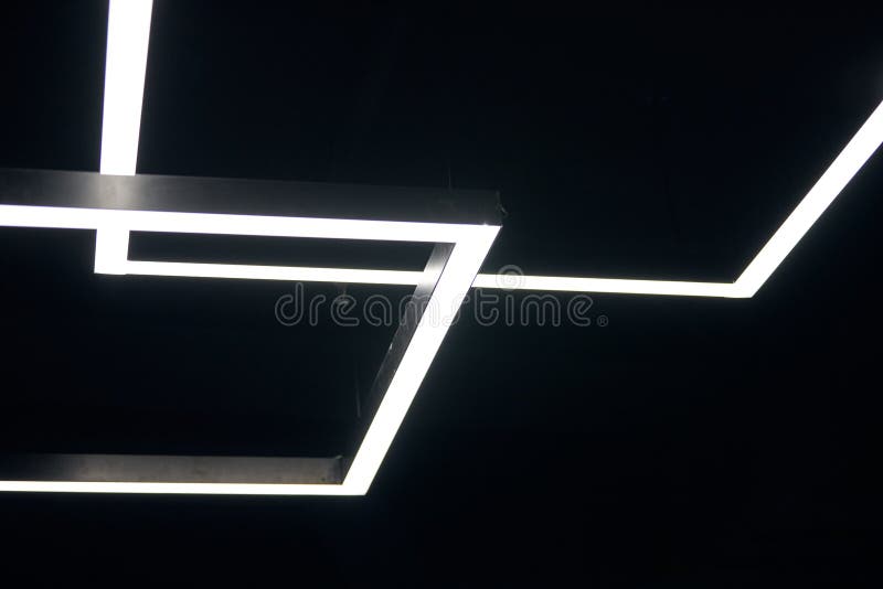 Modern office lighting. Thin lamps in office dark ceiling. LED white cold light over workplaces.