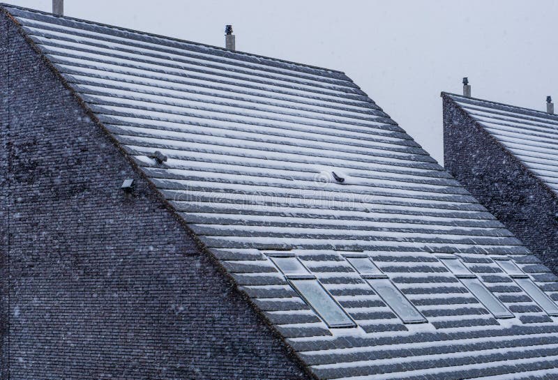 Modern pointy rooftop covered in snow during winter season, snowy cold weather, dutch architecture