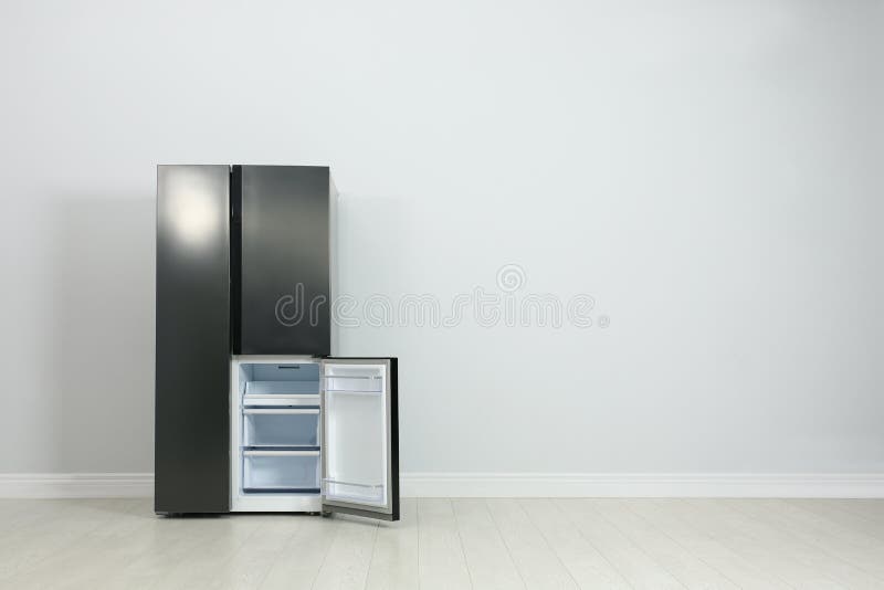 Modern Refrigerator Near Light Grey Wall. Space for Text Stock Photo