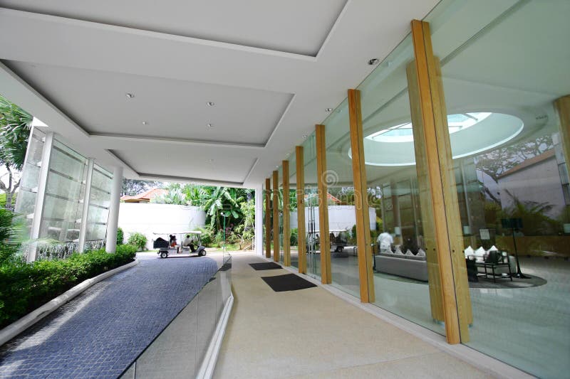 An exterior shot of a brand new modern five star holiday resort hotel on Sentosa island of Singapore. Cool contemporary architecture of glass, wood and steel combined with lush tropical landscaping for the exotic vacation mood. With a man-made waterfall feature on the left of the drive way. Small and light club car with canvas roof is used to ferry guests around the resort. Taken with a wide angle lens, horizontal color format. Man made waterfall stock images, royalty-free photos and pictures