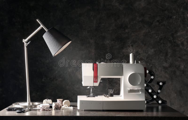 Modern Sewing Machine with Tailor S Supplies and Lamp on Table Near