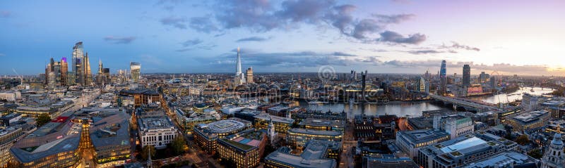 The modern skyline of London, United Kingdom, just after sunset: from the illuminated office buildings of the City along the Thames River with the famous Tower Bridge to Westminster