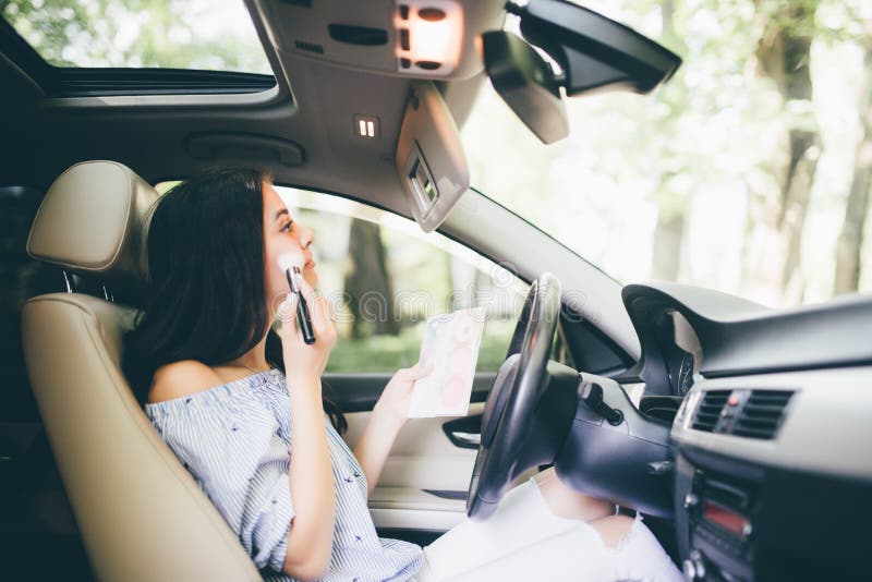 Modern smiling girl in car talk on phone and make-up on mirror royalty free stock photo Modern smiling girl in car talk on phone and make-up on mirror royalty free stock photo