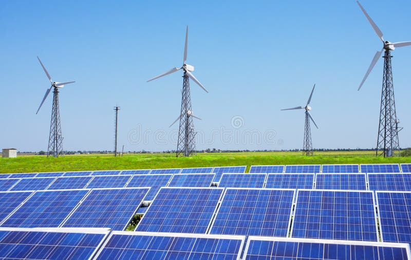 Modern solar station with blue panels and windfarm with wind tur