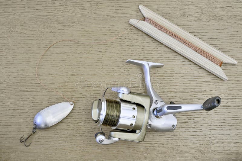 A Modern Spinning Reel with a Fishing Line and a Homemade Spoon with a Cord  Tied To it, Wound on a Wooden Reel Stock Image - Image of modern, metal:  135997493