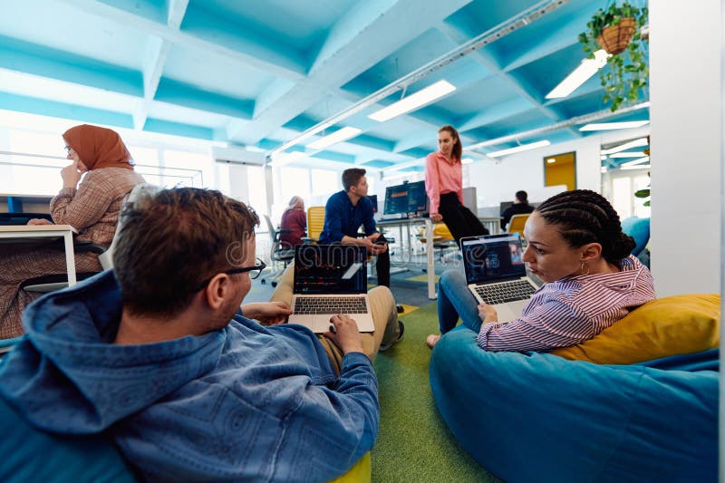 In a modern startup office, a diverse group of young and capable businesspeople engage in lively discussions about royalty free stock image