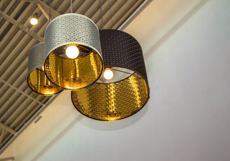 Modern stil brons dekorativa lampor, och guld- lampskärmar hänger på ett långt rep, det industriella taket, inredesign arkivfoton Modern stil brons dekorativa lampor, och guld- lampskärmar hänger på ett långt rep, det industriella taket, inredesign arkivfoton