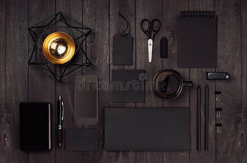 Modern stylish working place with blank black stationery, phone, coffee, gold decor on dark wood board. royalty free stock photos Modern stylish working place with blank black stationery, phone, coffee, gold decor on dark wood board. royalty free stock photos
