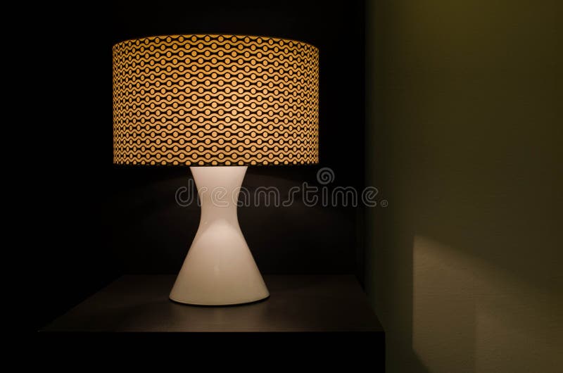 Modern table lamp on table illumination in the dark stock photo