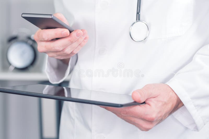 Modern technology in healthcare and medicine. Male doctor using smartphone and digital tablet computer in office stock photography Modern technology in healthcare and medicine. Male doctor using smartphone and digital tablet computer in office stock photography