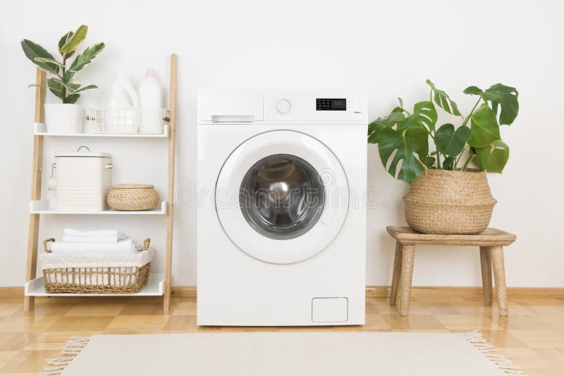 Modern washing machine and plants in rustic laundry room interior royalty free stock images