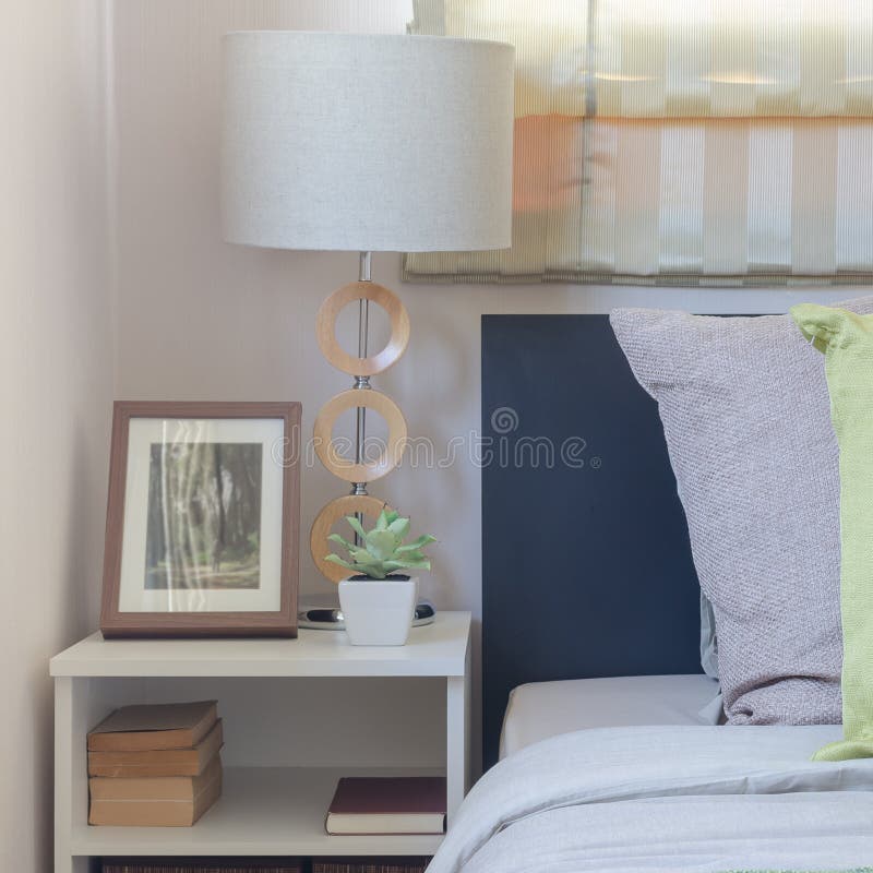 Modern white lamp on table with pillows on bed