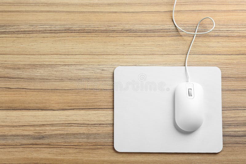 Modern wired optical mouse and pad on wooden table, top view. Space for text