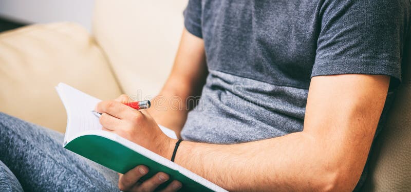 Left handed man writing, sitting on a sofa royalty free stock photography