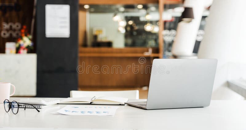 Modern workspace laptop and notebook on white table with blurred office room background royalty free stock photography