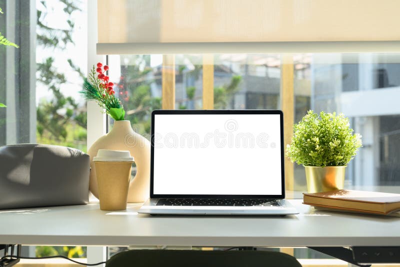 Modern workspace with laptop, plants, a coffee cup and notebook royalty free stock photo