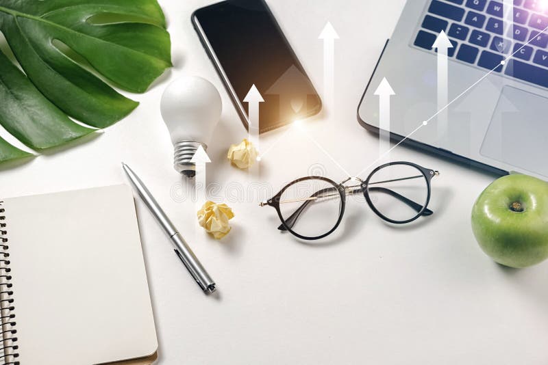 Modern workspace with light bulb, laptop, pen, monstera leaves, eyeglasses, fresh apple, smartphone and notebook royalty free stock photo Modern workspace with light bulb, laptop, pen, monstera leaves, eyeglasses, fresh apple, smartphone and notebook royalty free stock photo