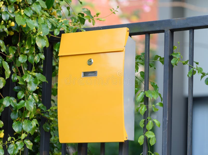 Modern Yellow Mail Box on Black Fence with Beautiful Yellows Background