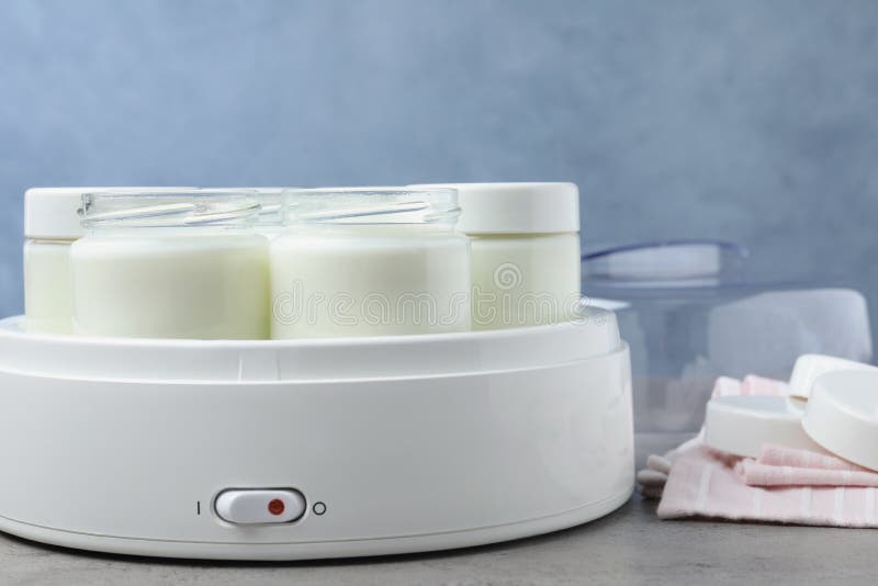 Modern Yogurt Maker with Full Jars on Grey Table, Closeup Stock Photo